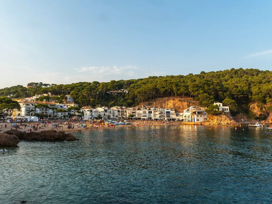 La badia de Tamariu des del mar, amb les cases blanques del poble i el pinar